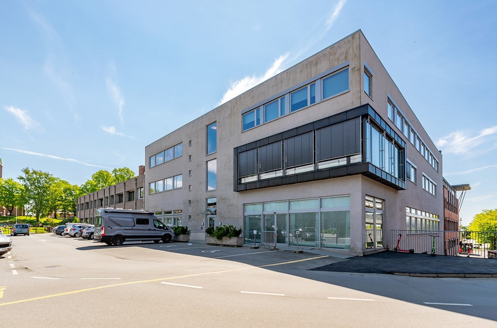 murbygning med parkeringsplass og biler