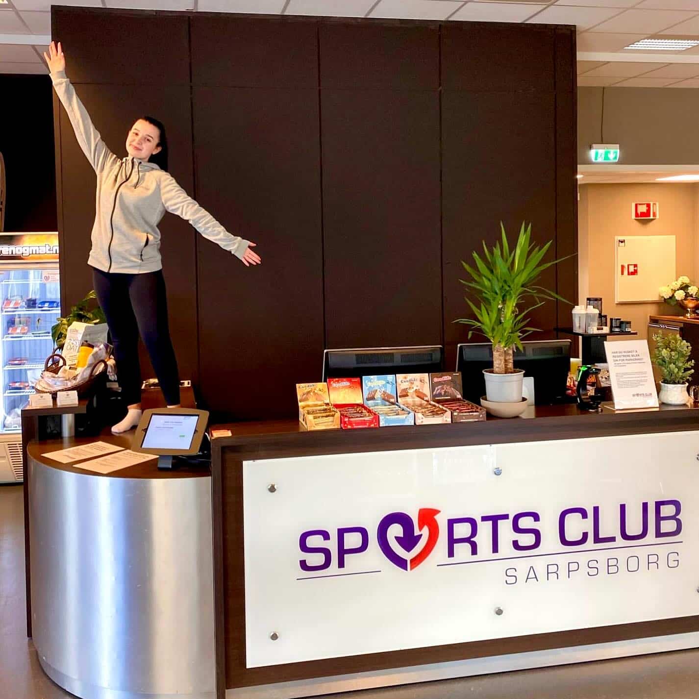 Ansatt ved Sports Club Sarpsborg stående på resepsjonsdesk